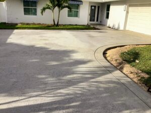 Newly installed curved concrete driveway in front of a residential home with palm trees
