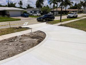 Freshly poured curved concrete driveway with caution tape around the work area