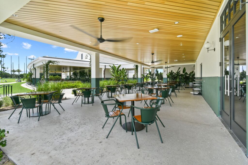 Outdoor dining patio with natural‑color shell broadcast concrete at a West Palm Beach golf club